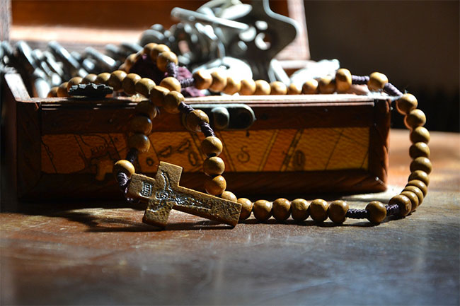 Foto di un rosario in legno adagiato su una bibbia