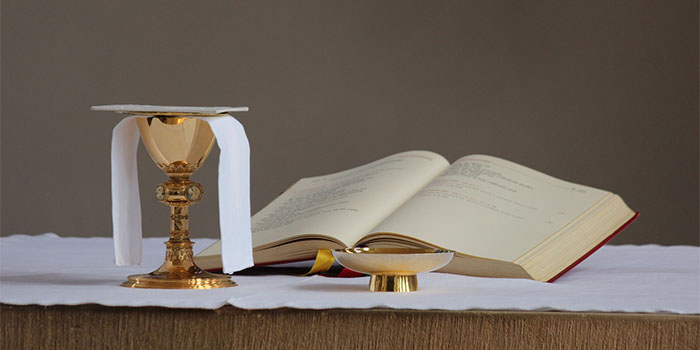 Immagine di un altare con un vangelo aperto e un calice e la Santa Eucarestia.